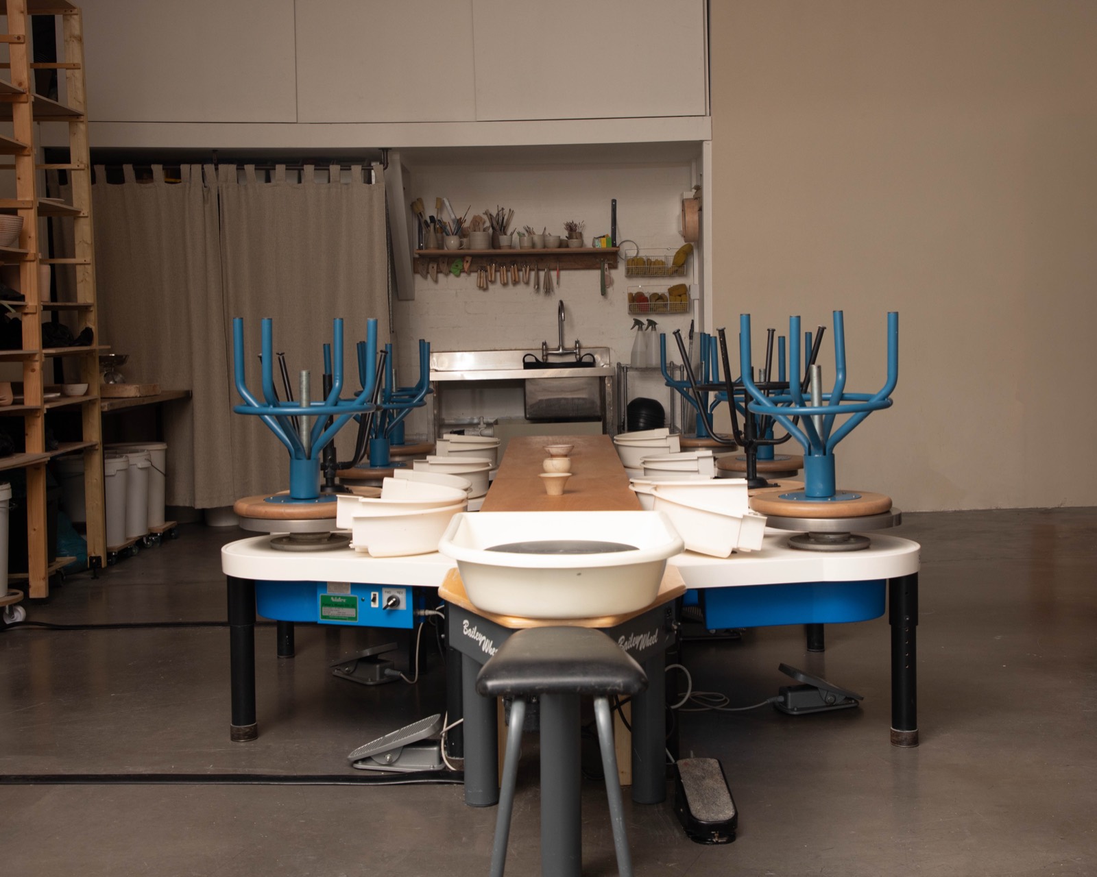 Nine pottery wheels arranged around the long communal table